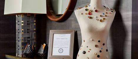 A mannequin with buttons, a framed sign, and a lamp on a table.