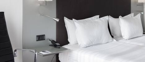 Una habitación de hotel moderna con una cama grande, un escritorio con teléfono y una silla.
