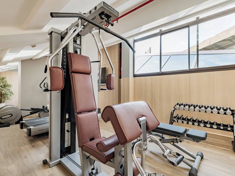 A gym with exercise equipment, a treadmill, and a dumbbell rack.