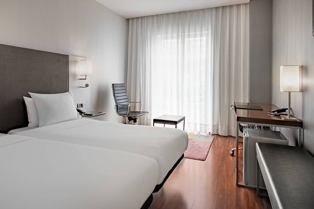 Een hotelkamer met een groot bed, een bureau, een stoel en een klein tafeltje.