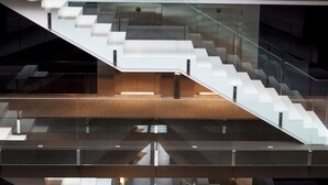 A multi-level interior with glass railings and wooden flooring.