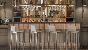 Zona de bar moderna con una barra central, taburetes y una variedad de botellas.
