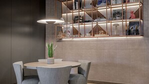 Un comedor moderno con una mesa redonda y cuatro sillas, una planta en maceta y una estantería con varios objetos decorativos.