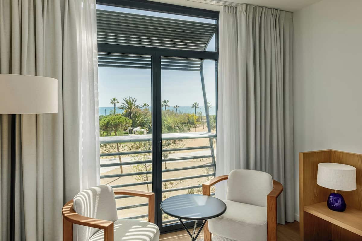 Ein Zimmer mit Blick auf den Strand, eine Couch, ein kleiner Tisch und eine Lampe.