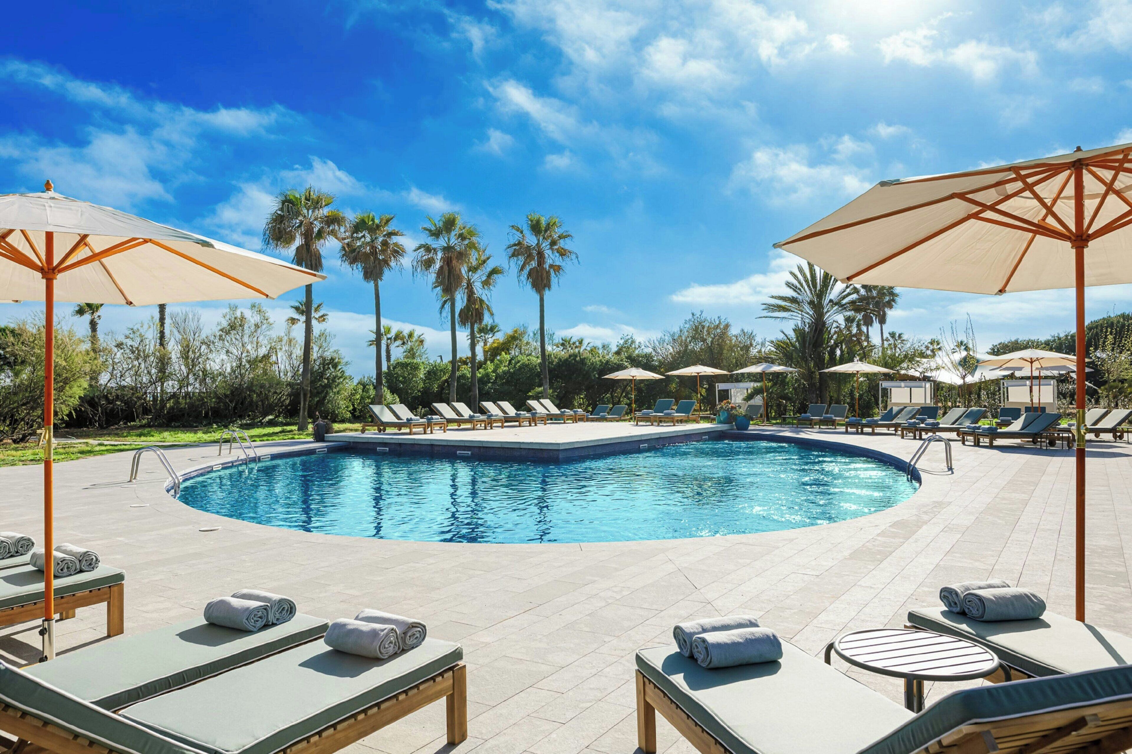 Een buitenzwembad, parasols voor strand/zwembad