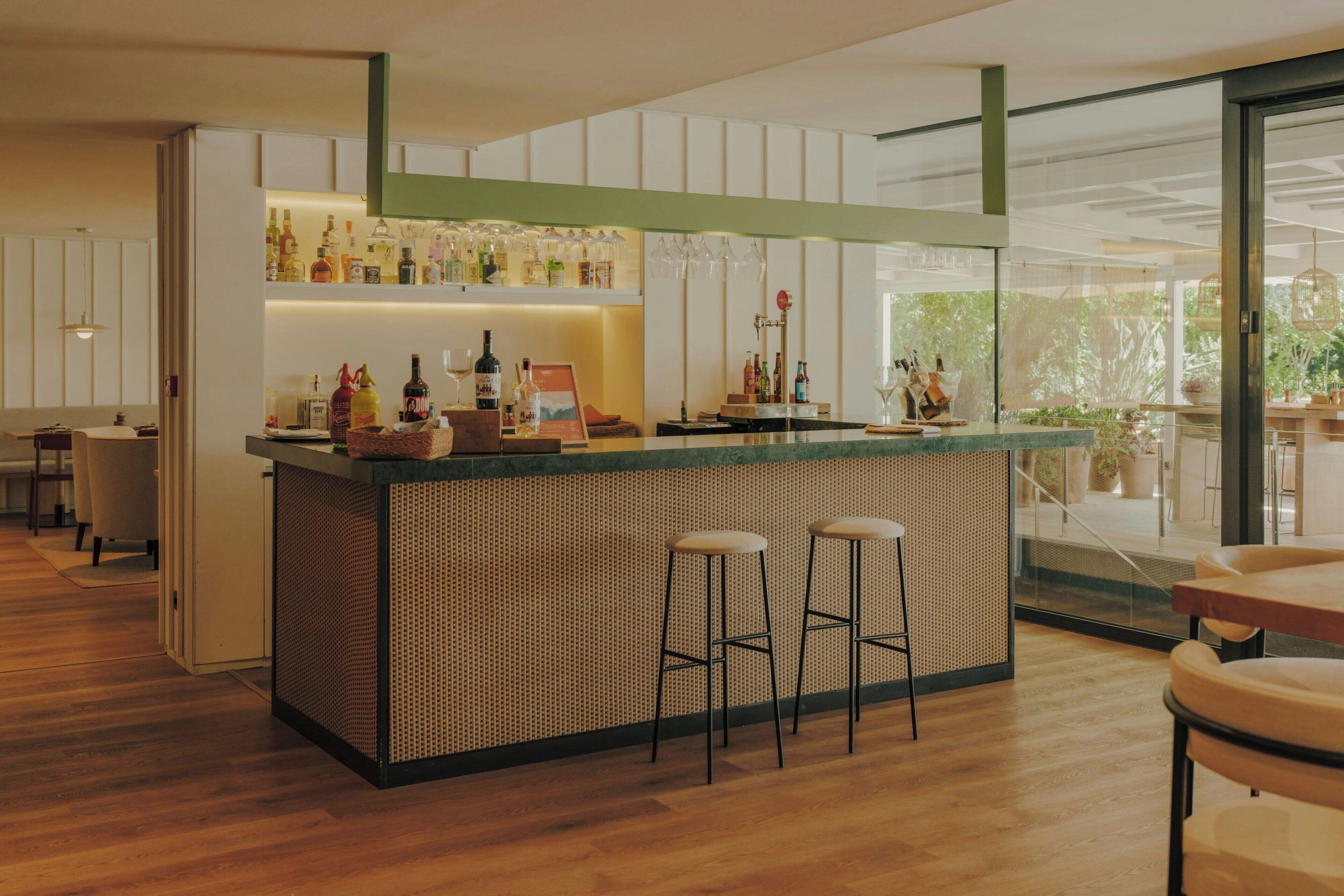 A modern bar area with a counter, stools, and a variety of bottles.