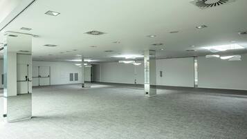 Una habitación amplia y moderna con techo alto, iluminación empotrada y piso alfombrado.
