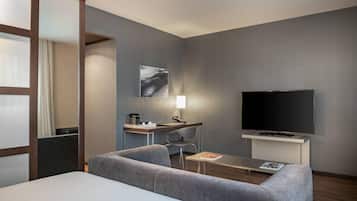 Una habitación de hotel moderna con una cama, un escritorio con televisor de pantalla plana, un sofá y una silla.