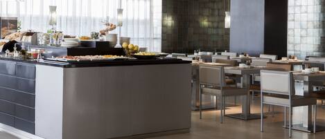 A modern dining area with a central buffet island, seating arrangements, and a large window with curtains.