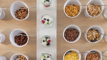 Un buffet de petit-déjeuner proposant une variété d’aliments, notamment des céréales, des yaourts et des fruits secs.