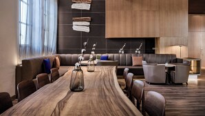 Een moderne vergaderruimte met een lange houten tafel, leren banken en een ingebouwde open haard.