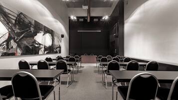 Un salón de conferencias con un cuadro abstracto grande en la pared, una mesa larga con sillas y un atril al frente.