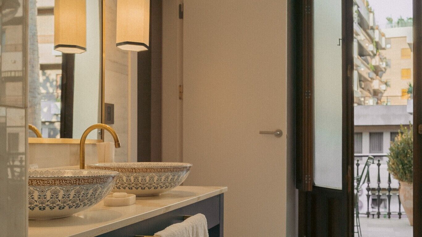 A bathroom with two large, ornate bowls on a vanity, a mirror, and a view of a balcony with outdoor furniture.