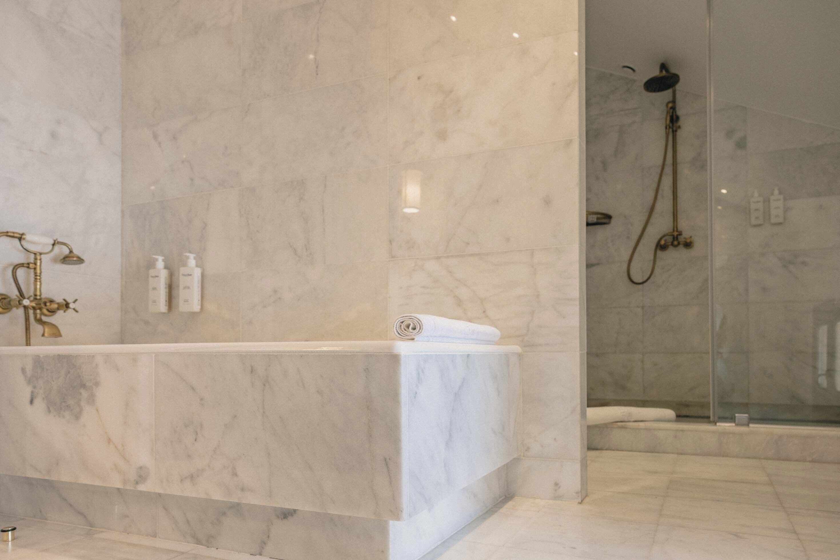 A bathroom with a marble sink, a shower, and a glass-enclosed shower area.
