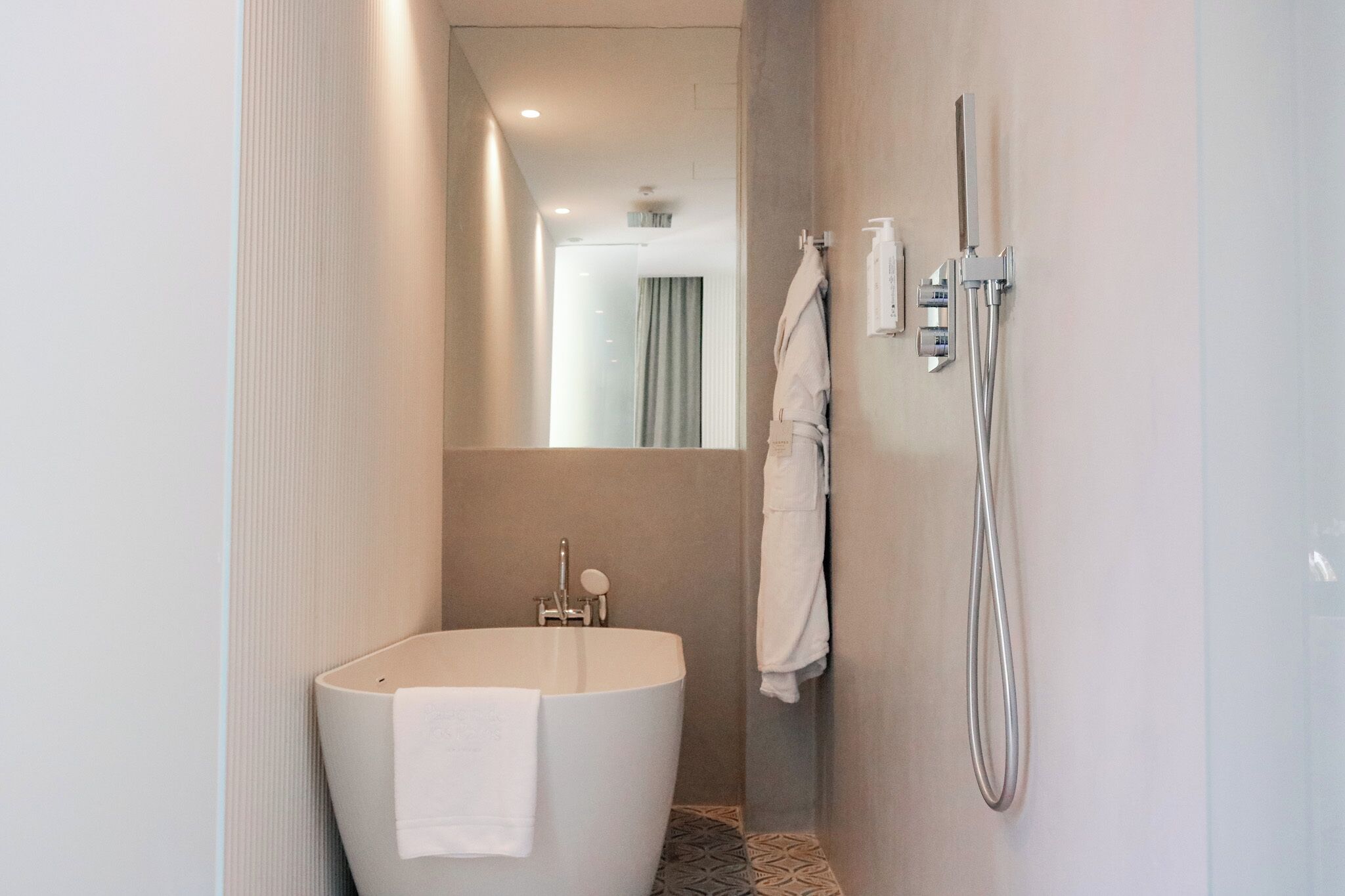 A modern bathroom with a freestanding bathtub, a handheld showerhead, and a towel rack.
