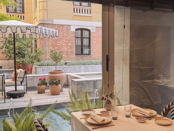 A dining area with a table set for two, a small fountain, and potted plants. - Hospes Palacio de los Patos, a Member of Design Hotels (Granada)