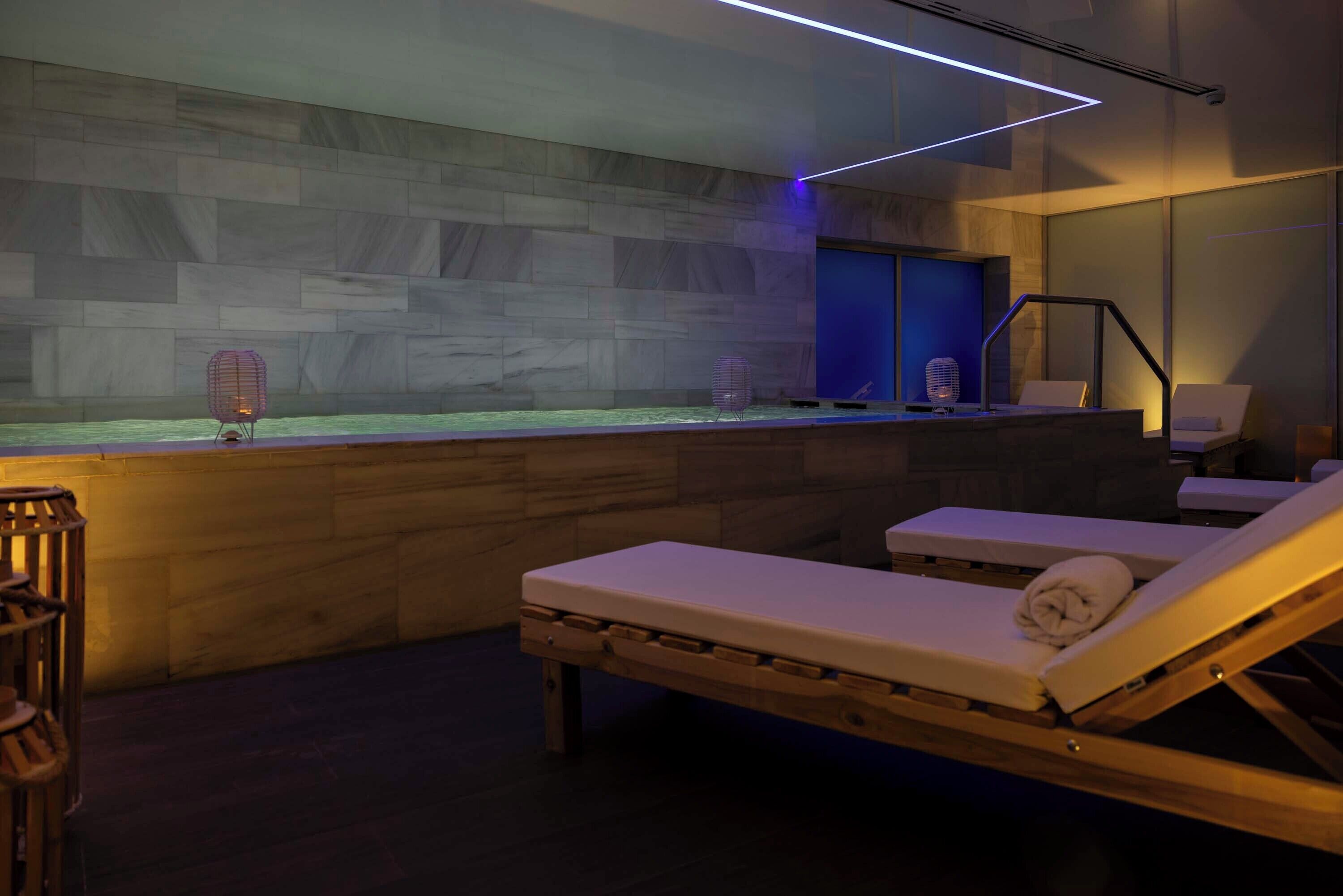 Un espace spa moderne doté d’un plancher en bois, d’un comptoir d’accueil et de fauteuils confortables.