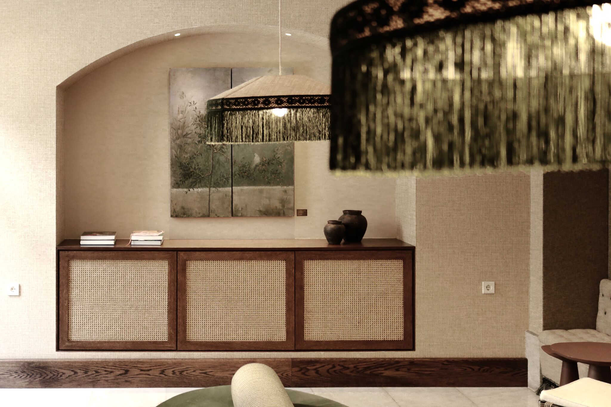 A room with a rattan console, a hanging lamp, and a painting on the wall.