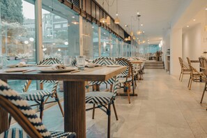 Een restaurant met een lange eetzône, houten stoelen en tafels gedekt met borden en glazen.
