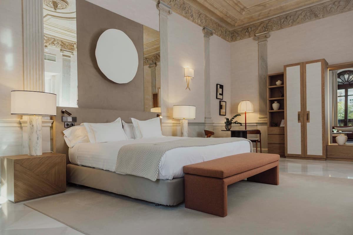 Ein geräumiges Schlafzimmer mit einem großen Bett, einem runden Spiegel und einem Kleiderschrank.