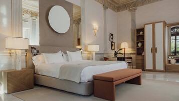 A spacious bedroom with a large bed, a round mirror, and a wardrobe.