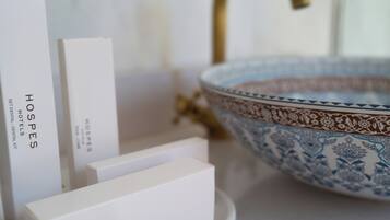 A bathroom with a white countertop, a gold faucet, and a decorative bowl.
