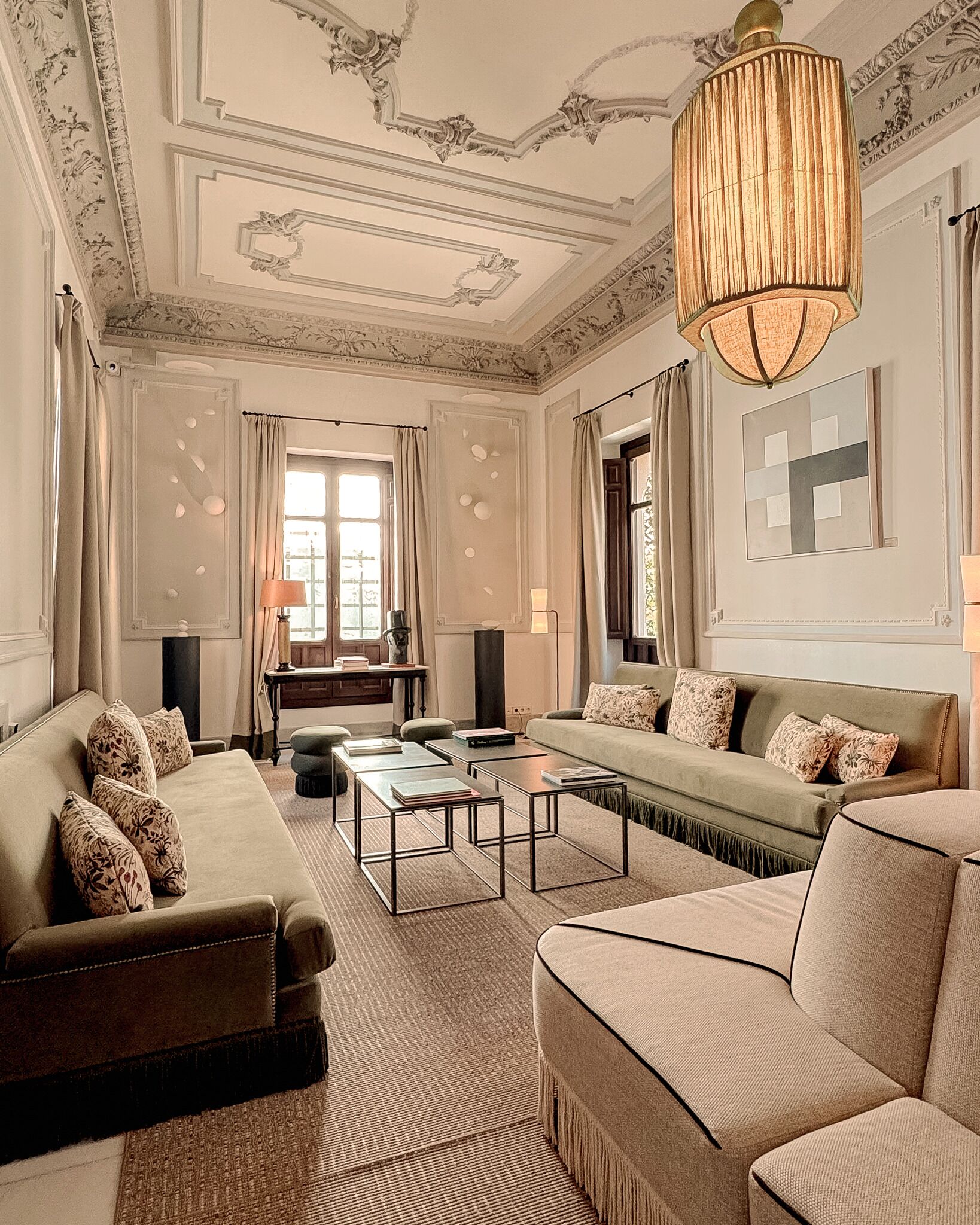 A spacious living room with a sofa, armchairs, a coffee table, and a chandelier.