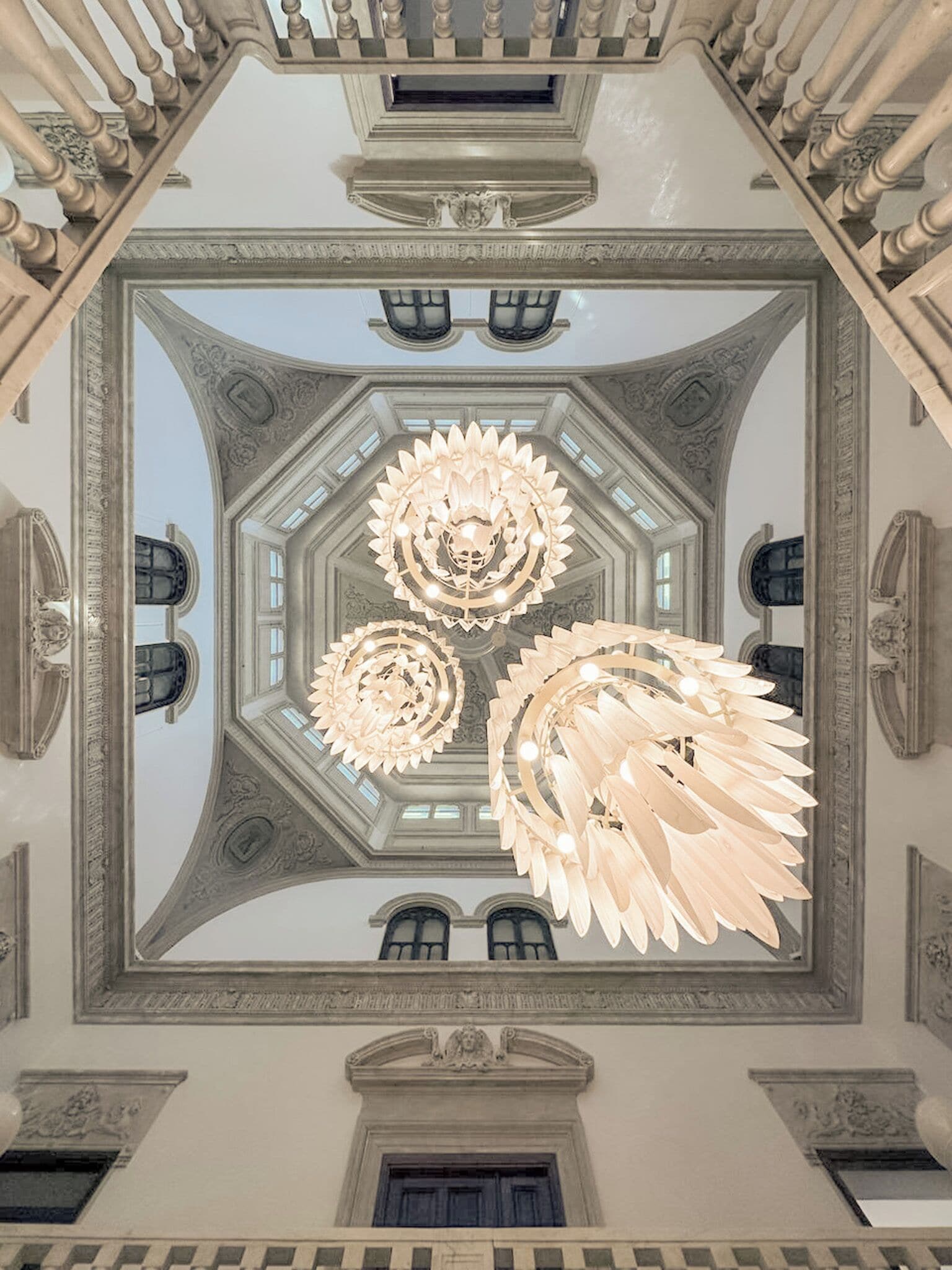 A grand hall with a symmetrical ceiling design, ornate chandeliers, and classical architectural details.