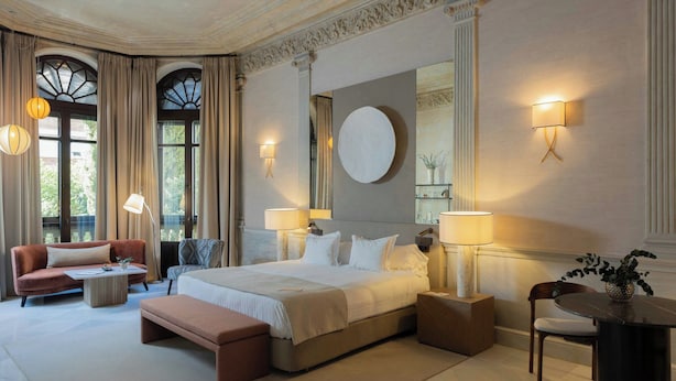 A hotel room with a large bed, two bedside tables, a sofa, a coffee table, and a chair. - Hospes Palacio de los Patos, a Member of Design Hotels (Granada)