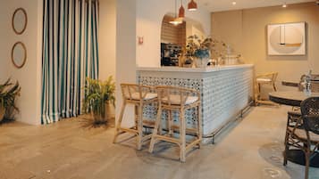 Un interior moderno con una zona de bar, sillas de mimbre y un suelo estampado.