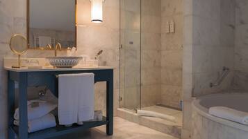 A modern bathroom with a dark blue vanity, a large mirror, a bowl sink, and a glass-enclosed shower.
