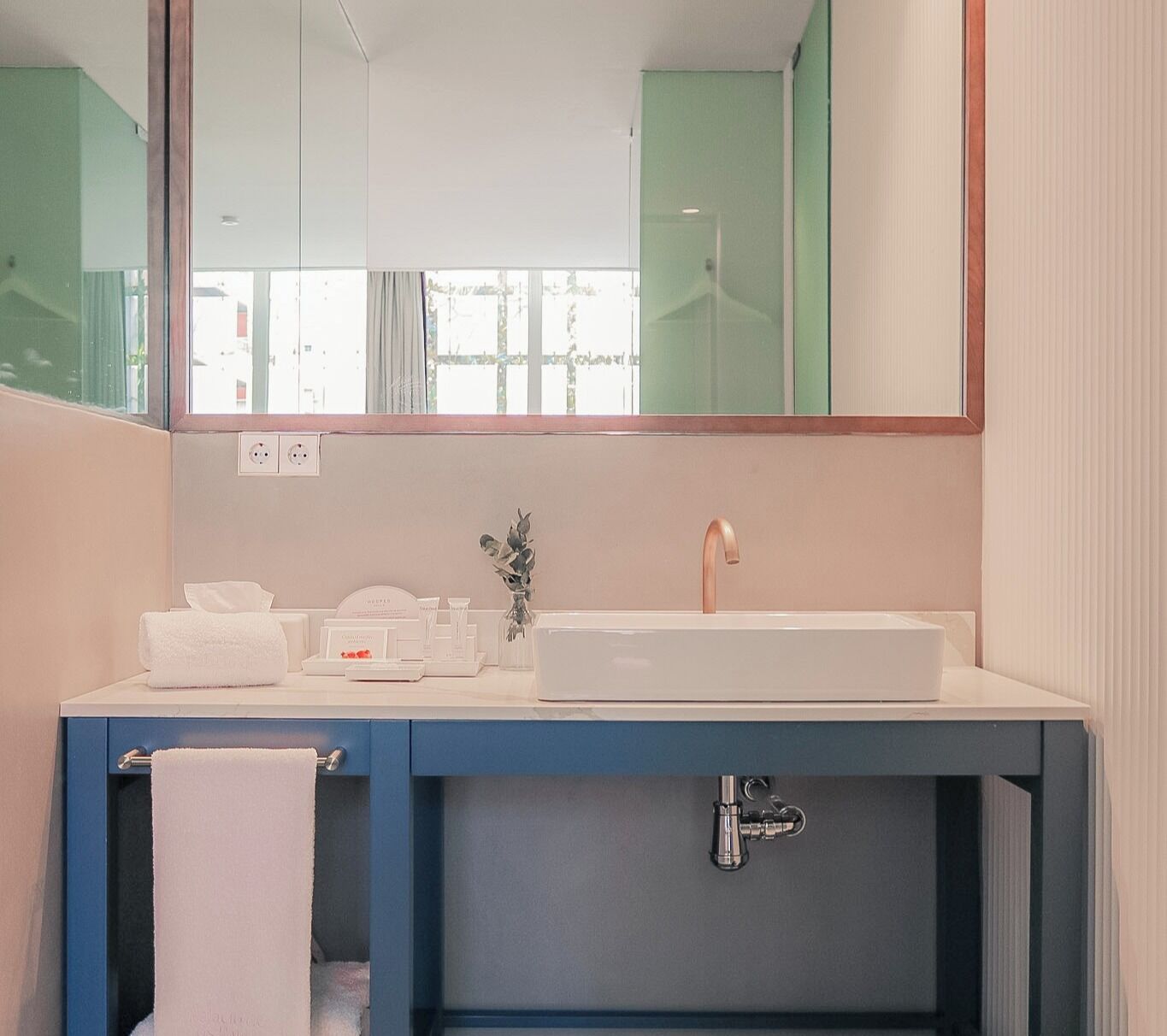 A modern bathroom with a white sink, a mirror above it, and a towel hanging on a rack.