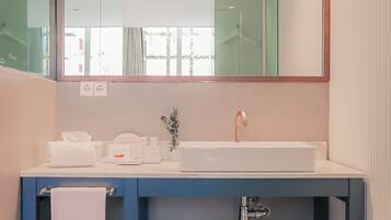 A modern bathroom with a white sink, a mirror above it, and a towel hanging on a rack.