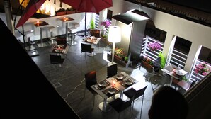Un espace de restauration intérieur avec des tables et des chaises, des parasols rouges et des plantes en pot.