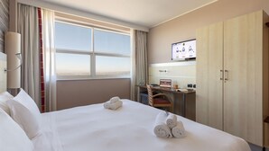 Een hotelkamer met een groot bed, een bureau, een televisie en een kledingkast.