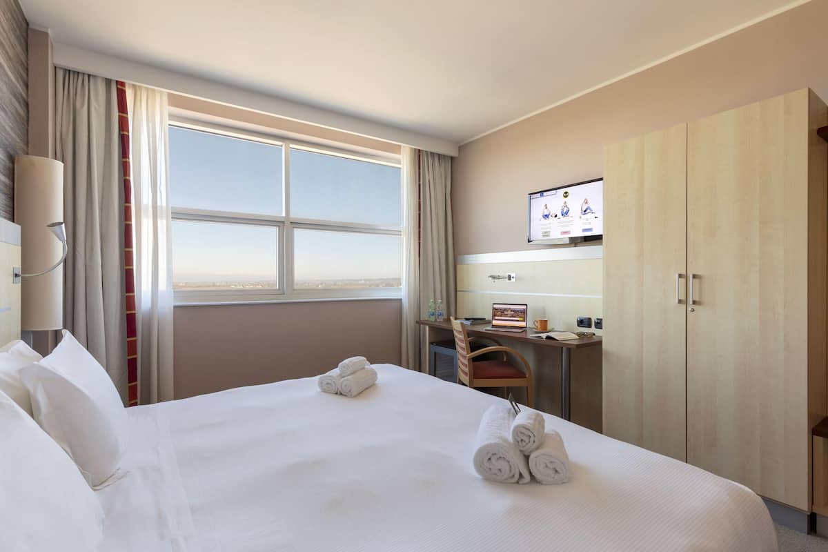 Een hotelkamer met een groot bed, een bureau, een televisie en een kledingkast.