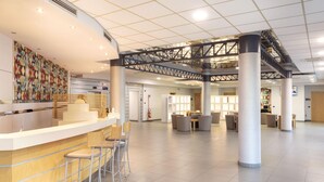 Een ruime lobby met een receptiebalie, een zithoek en een trap.