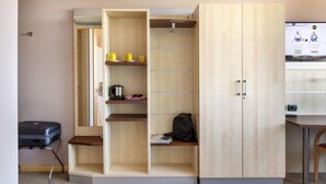 Een hotelkamer met een garderobe, een bureau en een koffer.