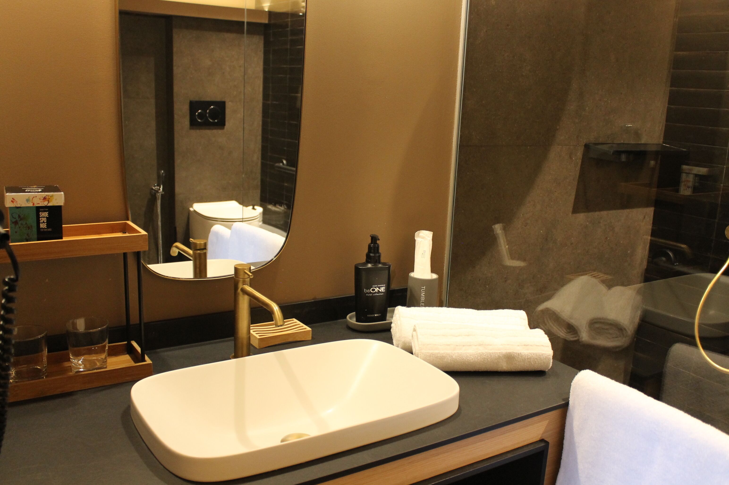 A modern bathroom with a large mirror, a sink, a toilet, and a towel rack.