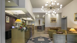 A hotel lobby with a reception desk, a chandelier, and seating area. - Hotel Falco D'Oro by Falco D'Oro Hotels (Vergato)