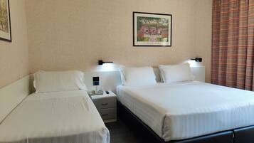 A hotel room with two beds, a nightstand, a wall-mounted lamp, and a framed picture.