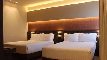 Habitación de hotel con dos camas, cabecera de diseño geométrico y lámpara de pared.