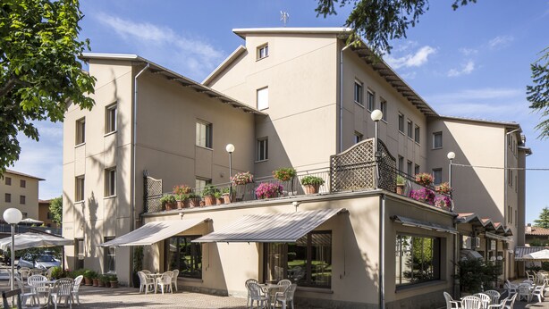 A building with outdoor seating and potted plants on the balcony. - Hotel Falco D'Oro by Falco D'Oro Hotels (Vergato)