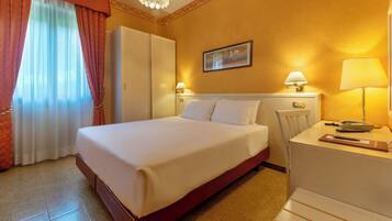 Une chambre d’hôtel avec un lit, un bureau avec un téléphone et une chaise.