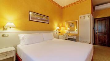 Une chambre d’hôtel avec un grand lit, des lampes de chevet, un bureau avec une chaise, un miroir et une porte.