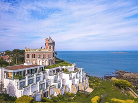 Um hotel à beira-mar com uma torre imponente, várias varandas e vista para o mar.