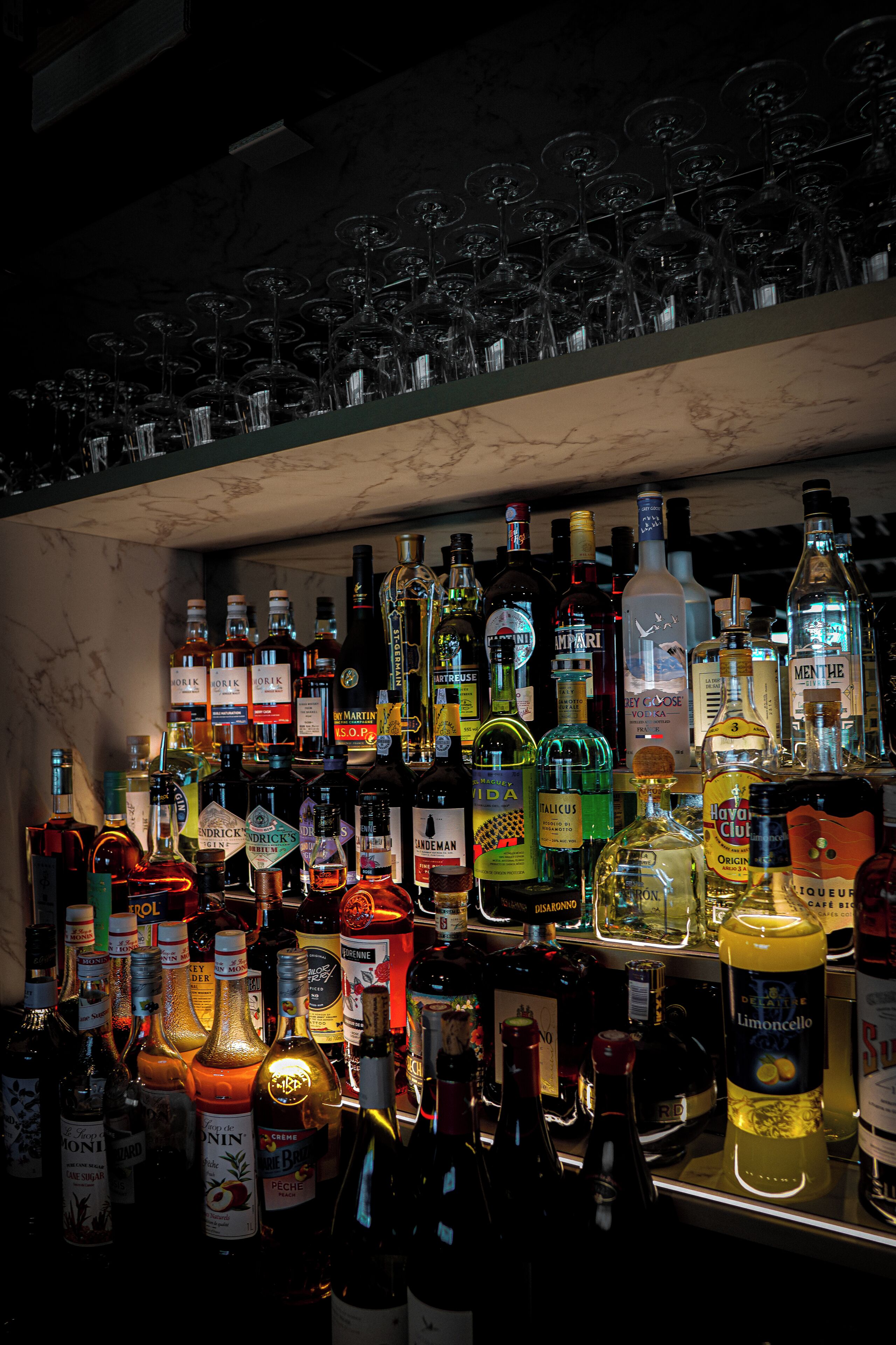 Un bar con una variedad de botellas de licor y copas de vino.