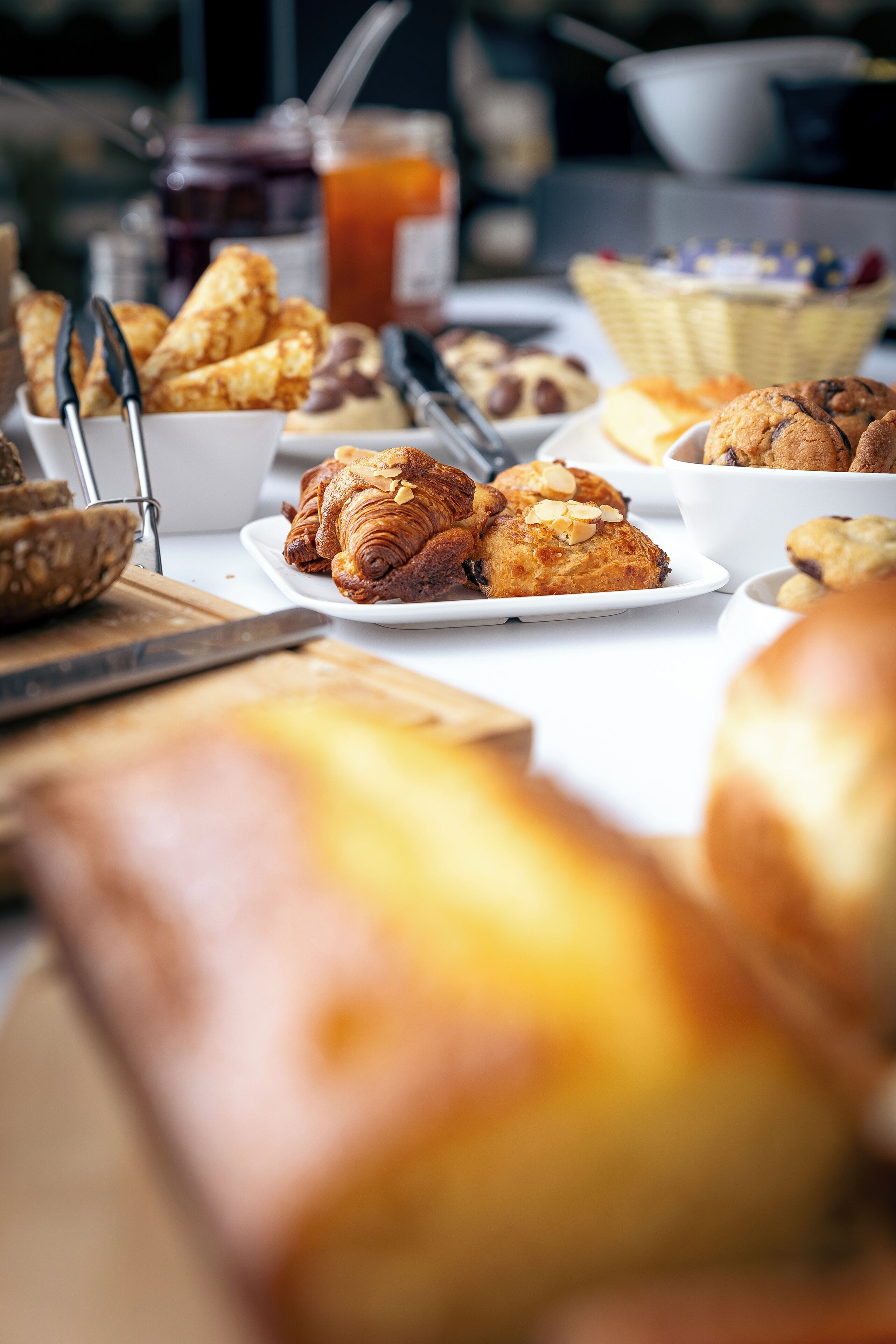 Una mesa con varios productos horneados, como croissants y pan, y un cuchillo sobre una tabla de cortar.