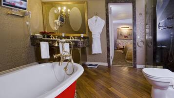 A bathroom with a red bathtub, a white toilet, a shower area, and a vanity with a mirror.