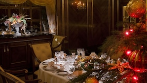 A formal dining room with a Christmas tree, elegant table settings, and classic furniture.